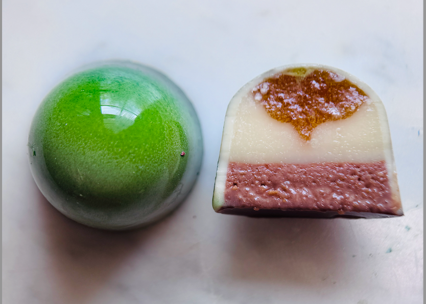 A refreshing bonbon with a tangy citrus gel, smooth cream cheese ganache, and a crisp graham cracker crunchy layer enrobed with white and milk chocolate